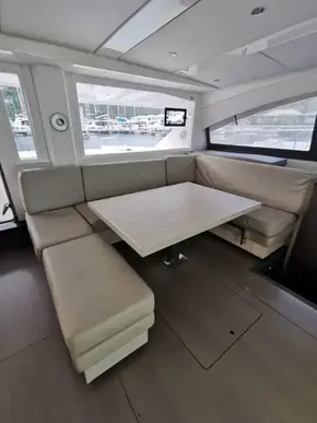 Interior seating area of 2017 Leopard 51 Powercat with beige cushions and a wooden table.