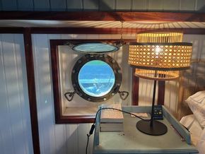 Cozy interior of 1901 Classic Dutch Barge with porthole and vintage lamp.