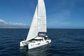 2024 Lagoon 42 catamaran sailing on open sea under clear blue skies.