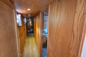 Interior hallway of a 1926 Dutch Barge Luxemotor, featuring wooden paneling and a small sink.