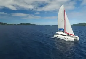 2020 Lagoon 42 catamaran sailing on open blue sea under a partly cloudy sky.