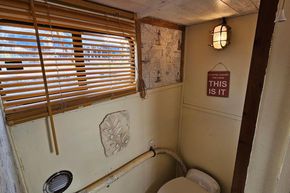 Interior of a 1927 Classic Dutch Barge bathroom with nautical decor and wooden blinds.
