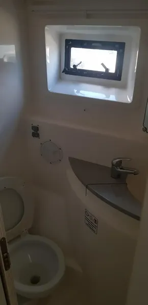 Compact bathroom in a 2017 Leopard 48 yacht with toilet, sink, and window.