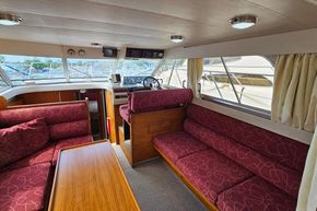 Interior of a 1989 Princess 35 Flybridge yacht with red patterned seating and wooden accents.