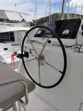 Steering wheel of a 2020 Lagoon 42 catamaran at a marina.