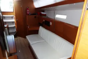 Interior of 2017 Jeanneau Sun Odyssey 389 sailboat with white sofa and wooden cabinetry.