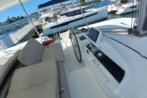 Helm of 2020 Lagoon 46 catamaran docked at marina, featuring navigation equipment.