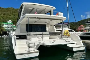 2022 Leopard 53 Powercat yacht docked in a marina, surrounded by lush greenery.