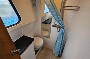 Compact bathroom in a 1921 Classic Dutch Barge with polka dot shower curtain.