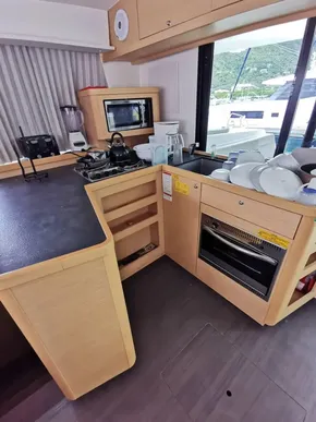 Modern kitchen interior of 2020 Lagoon 42 yacht with appliances and dishes.