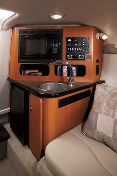 Crownline Cuddy Cabin 275 CCR - Galley features a stainless steel sink with fresh water, microwave, refrigerator and cherry wood cabinets