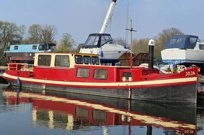 Classic 1927 Dutch Barge with red and cream exterior docked at a marina.