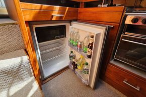 Open mini fridge in 1989 Princess 35 Flybridge yacht galley, stocked with beverages.