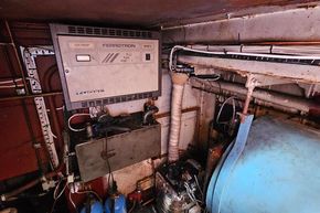 Engine room of a 1926 Dutch Barge Luxemotor with electrical equipment and piping.