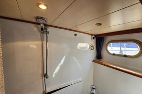 Shower area inside 2005 Stevens 1200 Vlet boat with porthole and wooden accents.