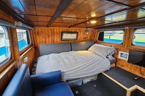 Cozy 1921 Classic Dutch Barge interior with wooden paneling and comfortable bed.
