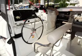Lagoon 42 catamaran helm station, 2020 model, docked at a marina with scenic background.