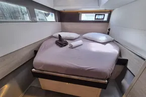 Cozy bedroom in 2021 Leopard 45 yacht with neatly arranged bed and windows.