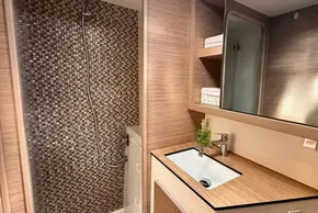 Modern bathroom in 2024 Lagoon 42 yacht with wood accents and mosaic shower tiles.