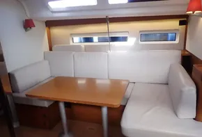 Interior of 2019 Jeanneau Sun Odyssey 440 yacht with white seating and wooden table.