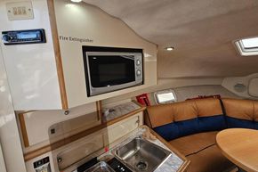 1998 Maxum 2400 SCR cabin interior with microwave, sink, and seating area.