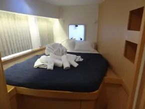 Cozy bedroom in 2020 Lagoon 42 catamaran with a neatly made bed and window.