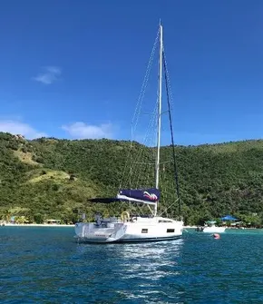 2020 Beneteau Oceanis 46.1 sailboat on clear blue water near lush green hills.