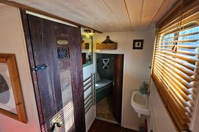 Interior of a 1927 Classic Dutch Barge with wooden door, cozy cabin, and small sink.