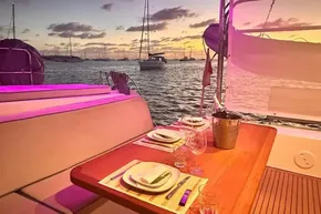 Luxurious dining setup on 2024 Lagoon 42 yacht at sunset, with ocean view.