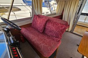 Interior of 1989 Princess 35 Flybridge yacht with red patterned seating and steering wheel.
