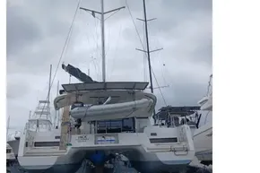 2024 Lagoon 42 catamaran on land, under cloudy sky, with masts and rigging visible.