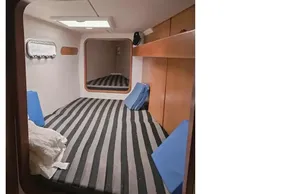 Cozy cabin interior of 2008 Leopard 38 catamaran with striped bedding and wooden accents.