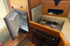 1991 Sealine 290 Ambassador kitchen with open fridge, stove, and wooden cabinetry.