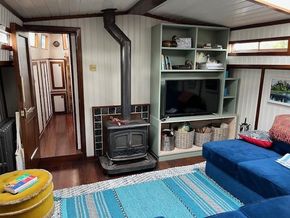 Cozy interior of a 1901 Classic Dutch Barge with wood stove and modern furnishings.