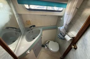 1991 Sealine 290 Ambassador bathroom with sink, toilet, and window.