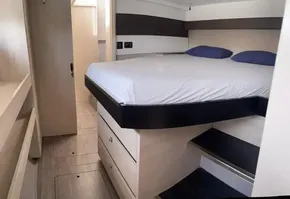 Modern bedroom interior of Leopard 50 yacht, 2020 model, featuring a raised bed and wooden cabinetry.