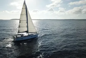 Sailing yacht Beneteau Oceanis 41, 2013 model, gliding on open sea under clear skies.