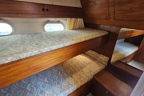 Interior of 1989 Princess 35 Flybridge with wooden bunk beds and porthole windows.