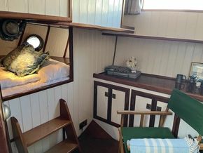 Cozy interior of a 1901 Classic Dutch Barge with bed, typewriter, and wooden furnishings.