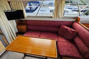 Interior of 1989 Princess 35 Flybridge yacht with red patterned seating and wooden table.