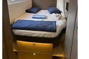 Luxurious cabin interior of 2022 Leopard 42 yacht with cozy bedding and ambient lighting.