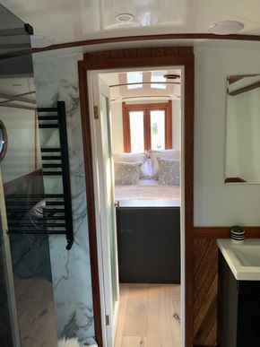 view through marble floored generous bathroom to full sized double bed master suite
