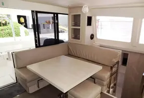 2017 Leopard 43 Powercat interior dining area with beige seating and wooden table.