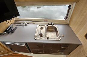 Compact kitchen area in 2023 Balt 818 Titanium boat with sink, stove, and TV.