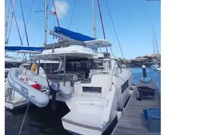 2022 Leopard 45 catamaran docked at marina, featuring blue sails and inflatable dinghy.