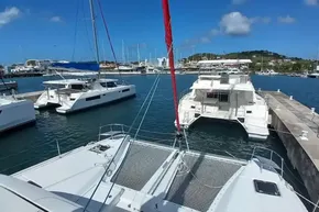 2020 Lagoon 46 catamaran docked in a sunny marina with other boats.