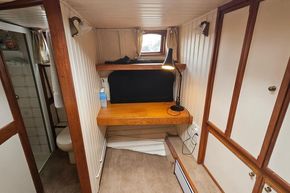 Cozy interior of a 1926 Dutch Barge Luxemotor with desk, lamp, and bathroom.