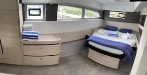 Modern bedroom interior of Leopard 50 yacht, 2020 model, with bed, drawers, and windows.