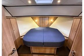 Luxurious cabin interior of 2025 Linssen 45 SL Sedan yacht, featuring cozy bed and wooden finish.