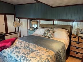 Cozy bedroom inside a 1901 Classic Dutch Barge with vintage decor and comfortable bedding.